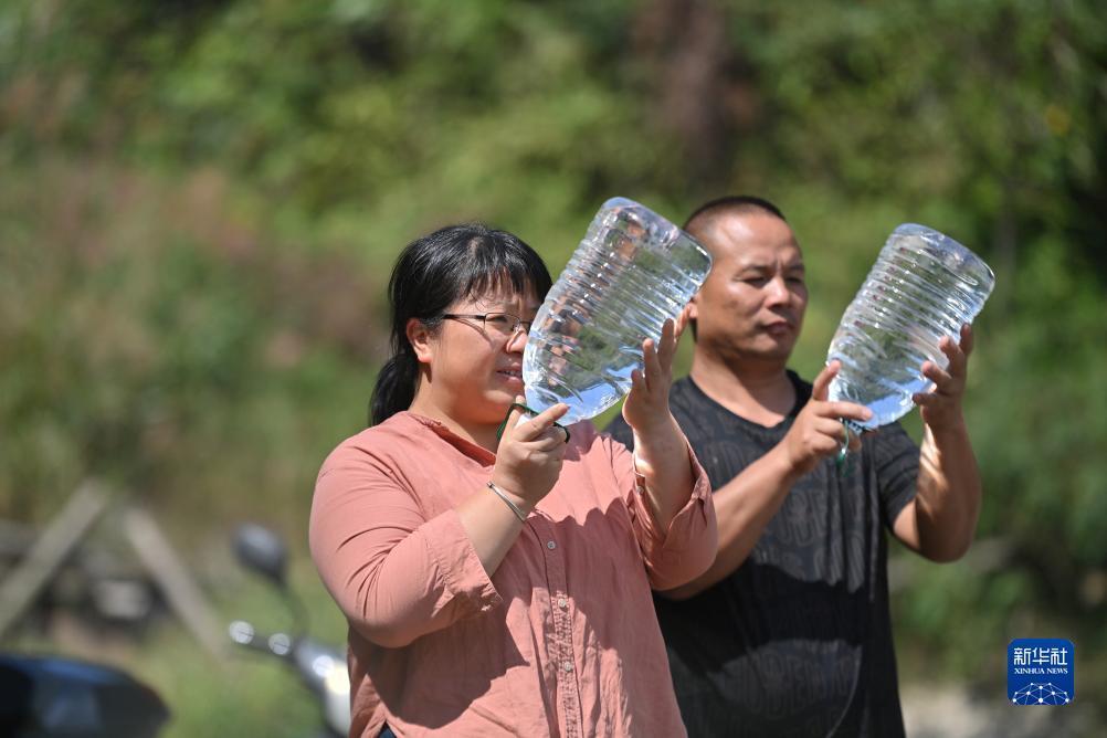 楊寧（左）在查看村民剛剛采集的水樣，為山泉水引水工程做準(zhǔn)備（10月8日攝）。新華社記者 黃孝邦 攝